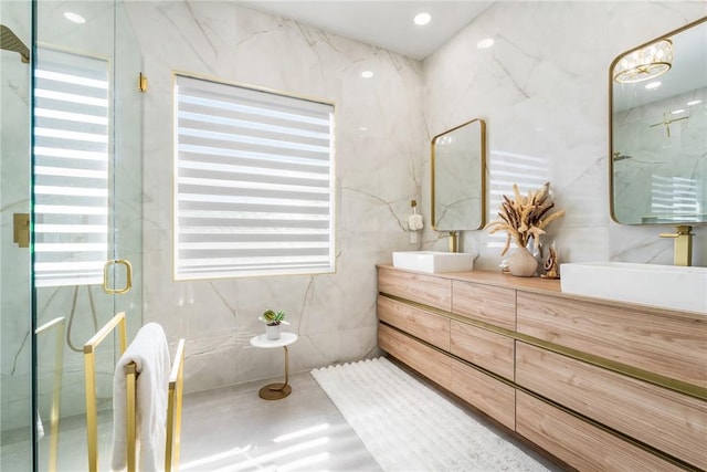 full bath with a marble finish shower, vanity, and tile walls