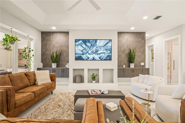 living area featuring a raised ceiling, recessed lighting, visible vents, and ceiling fan