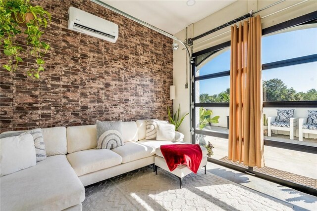 living area with brick wall, a garage, and a wall mounted air conditioner