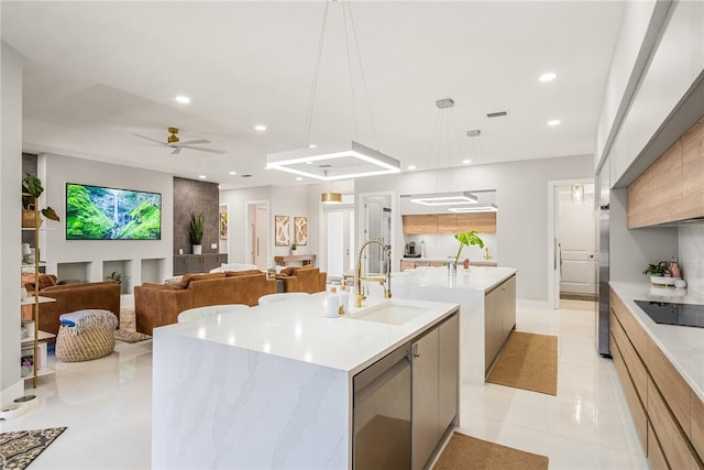 kitchen with modern cabinets, stainless steel refrigerator, a sink, light countertops, and a large island with sink