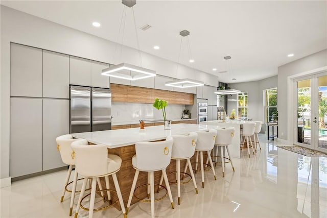 kitchen with appliances with stainless steel finishes, modern cabinets, light countertops, and french doors