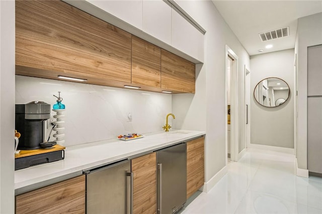 bar featuring fridge, baseboards, and visible vents