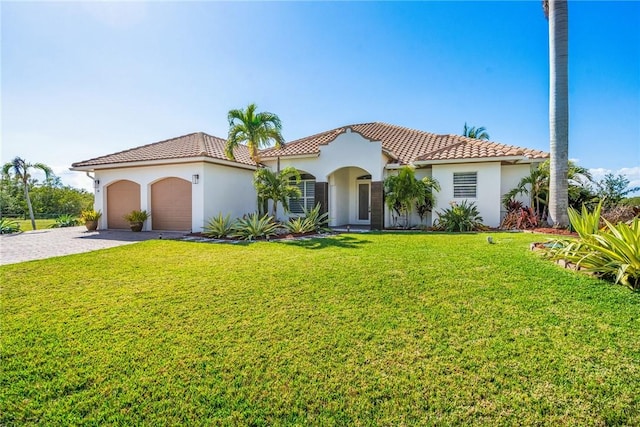 mediterranean / spanish-style home featuring decorative driveway, a front yard, a tiled roof, and an attached garage