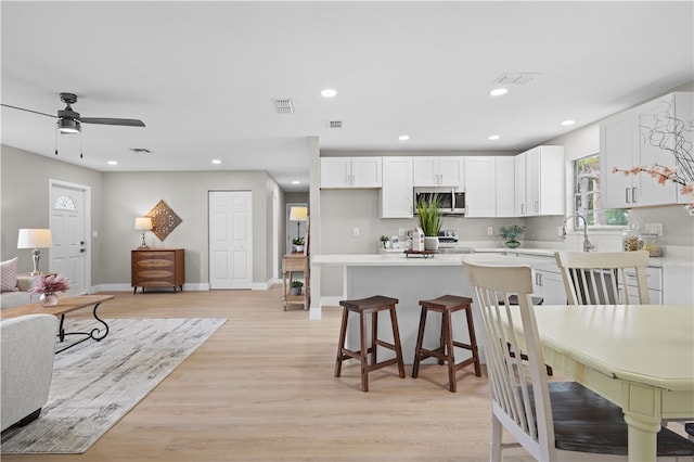 kitchen with range with electric cooktop, stainless steel microwave, visible vents, and white cabinetry