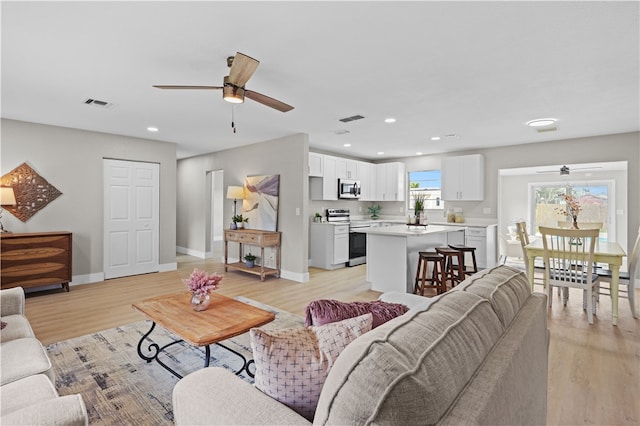 living area featuring light wood-style flooring, recessed lighting, visible vents, and baseboards