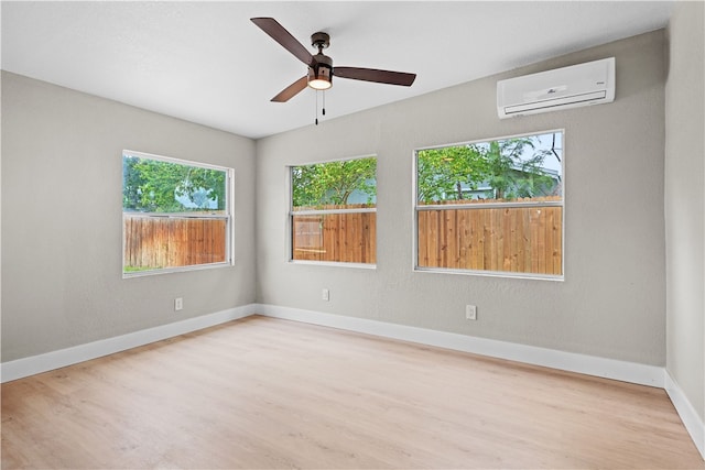 spare room with a ceiling fan, baseboards, an AC wall unit, and wood finished floors