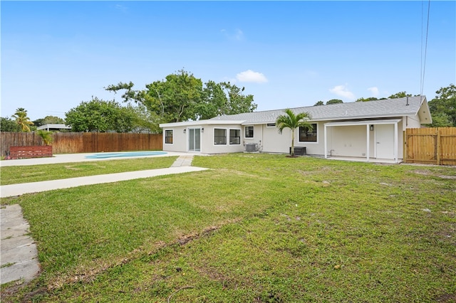 rear view of property featuring a yard, a fenced backyard, a fenced in pool, and central air condition unit