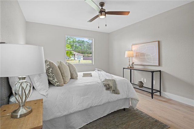 bedroom with a ceiling fan, baseboards, and wood finished floors