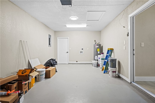 interior space featuring a garage door opener, electric water heater, and baseboards