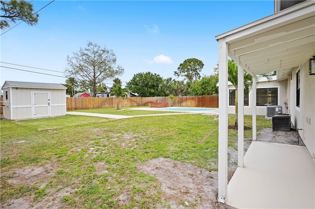 view of yard featuring a fenced backyard, an outbuilding, a fenced in pool, and a shed