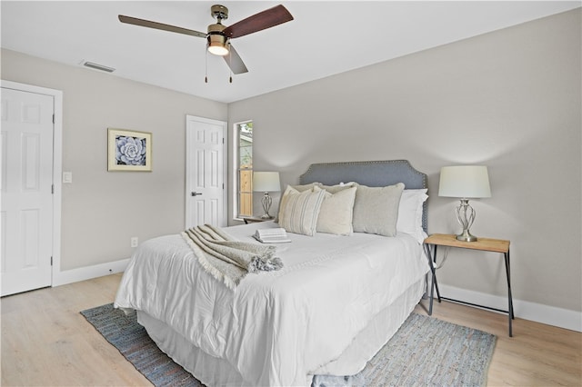 bedroom with baseboards, visible vents, and wood finished floors