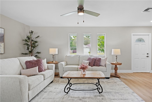 living area featuring a ceiling fan, baseboards, visible vents, and wood finished floors