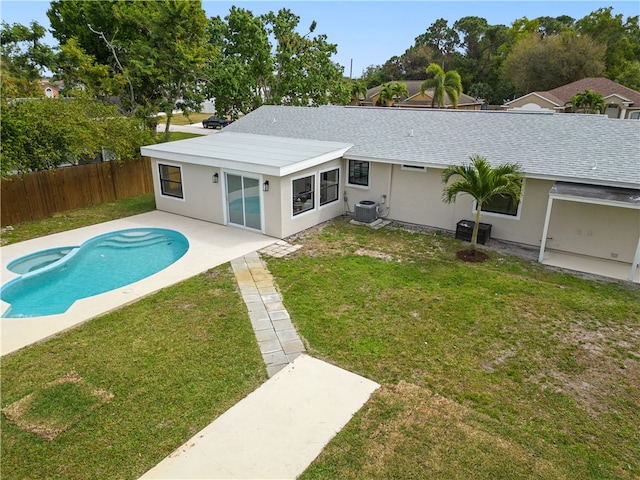 rear view of house with stucco siding, central air condition unit, a lawn, a patio area, and a fenced backyard