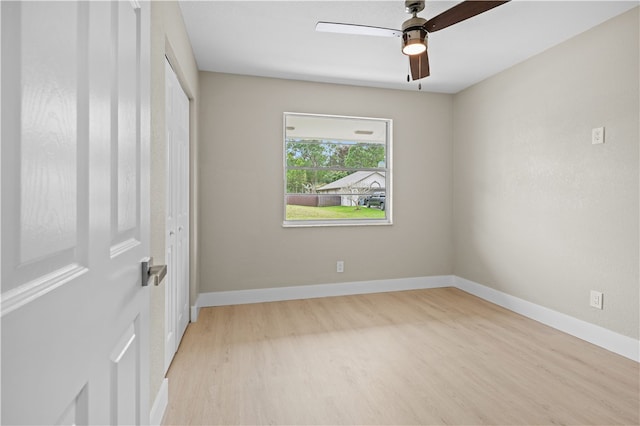 empty room with ceiling fan, light wood-style flooring, and baseboards