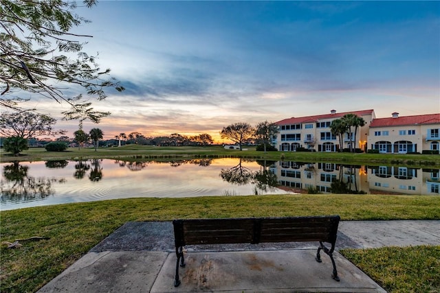 view of property's community with a water view and a lawn