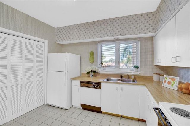 kitchen with light tile patterned flooring, sink, white cabinetry, tile walls, and white appliances