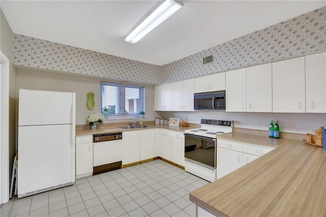 kitchen featuring white appliances, light tile patterned floors, sink, and white cabinets