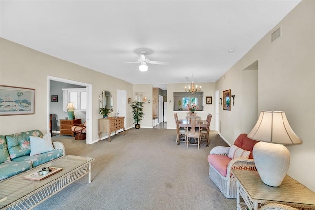 carpeted living room with ceiling fan with notable chandelier