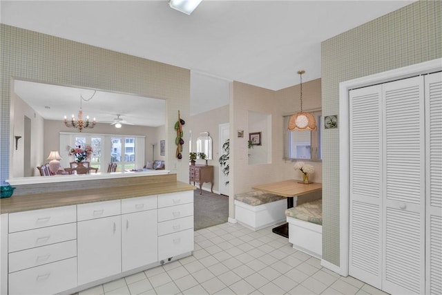 interior space with hanging light fixtures, white cabinetry, ceiling fan with notable chandelier, and light tile patterned flooring