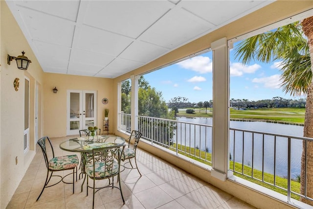 sunroom featuring a drop ceiling, french doors, and a water view