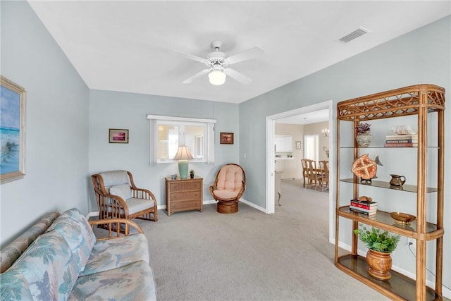 living area featuring light colored carpet and ceiling fan