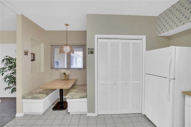 kitchen featuring white refrigerator, pendant lighting, light tile patterned floors, and breakfast area