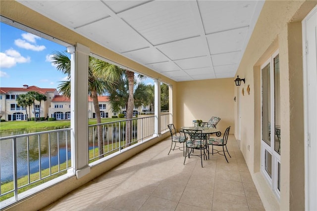 sunroom featuring a water view, a healthy amount of sunlight, and a paneled ceiling