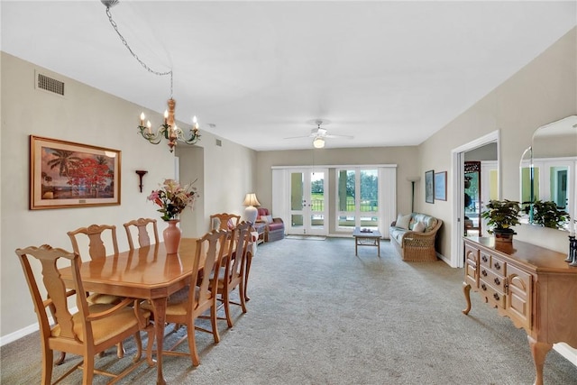 carpeted dining area featuring french doors and ceiling fan with notable chandelier