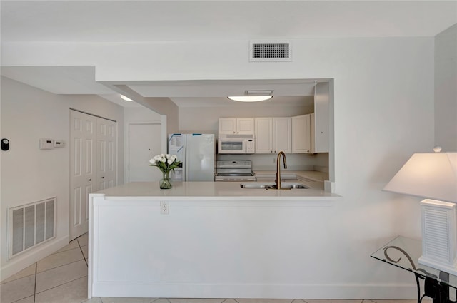 kitchen featuring white cabinetry, sink, light tile patterned flooring, white appliances, and kitchen peninsula