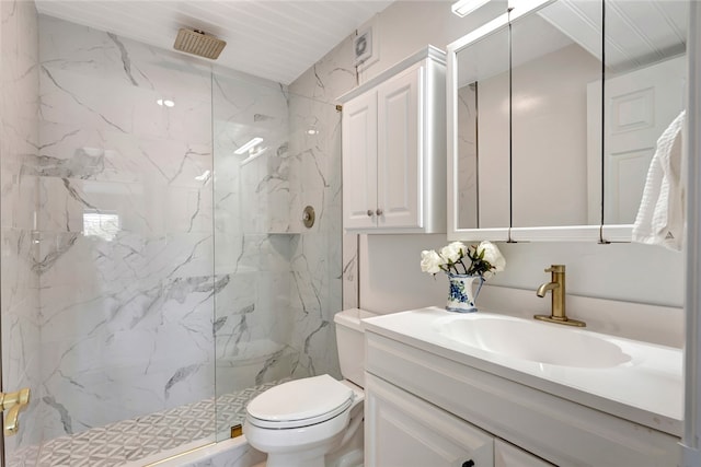 bathroom with tiled shower, vanity, and toilet