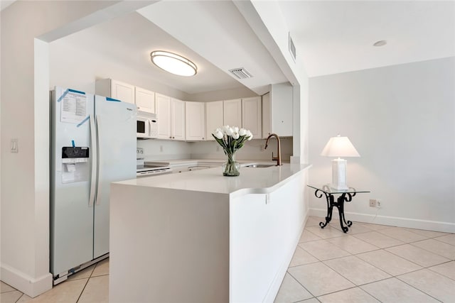 kitchen featuring kitchen peninsula, white appliances, sink, white cabinetry, and light tile patterned flooring