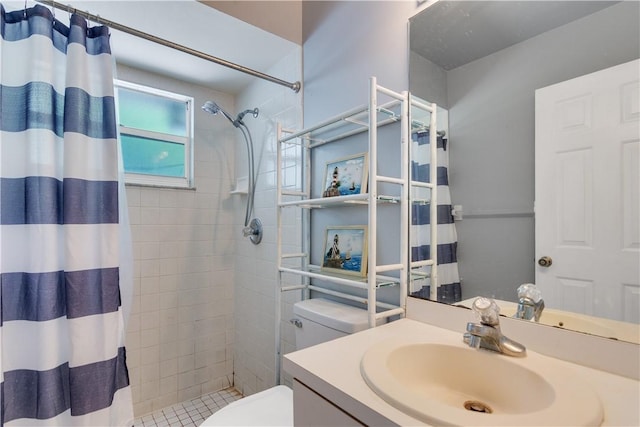 full bathroom with a tile shower, toilet, and vanity