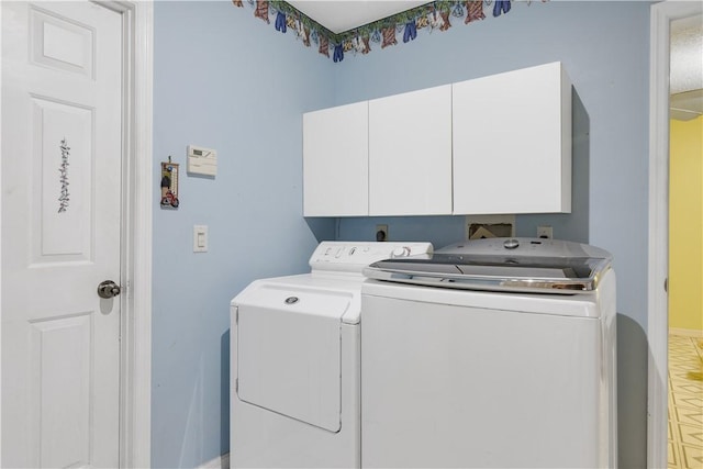 washroom featuring baseboards, washing machine and clothes dryer, and cabinet space