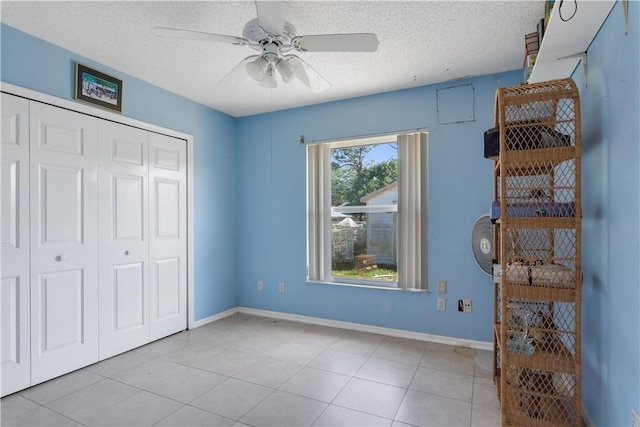unfurnished bedroom featuring a closet, baseboards, light tile patterned flooring, and a textured ceiling