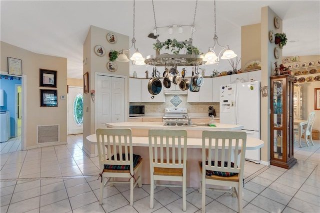 kitchen with visible vents, light tile patterned floors, an inviting chandelier, white appliances, and a towering ceiling