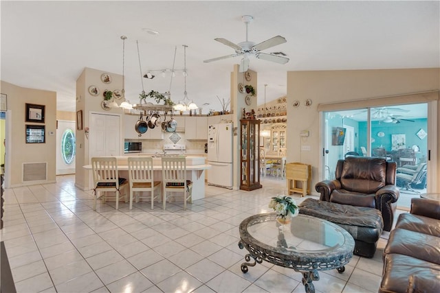 living area featuring light tile patterned flooring, ceiling fan with notable chandelier, and high vaulted ceiling