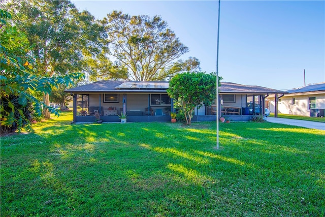 view of front of house featuring a sunroom, solar panels, and a front lawn