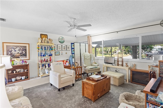 carpeted living room featuring ceiling fan and a textured ceiling