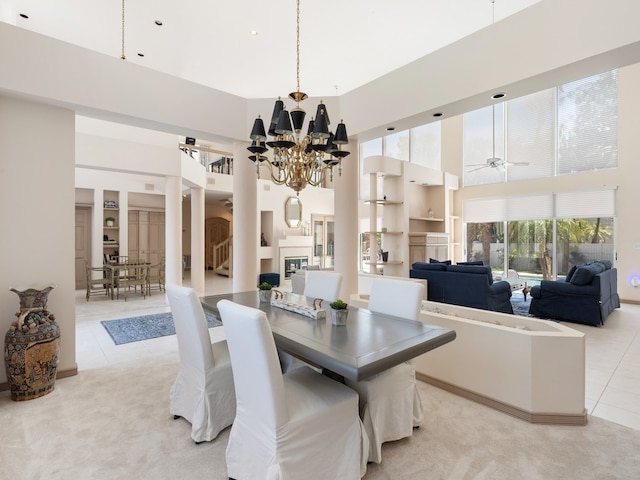 dining room with ceiling fan with notable chandelier, light tile patterned flooring, and a high ceiling