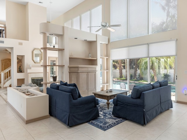 living room featuring ceiling fan, light tile patterned floors, a high ceiling, and built in shelves