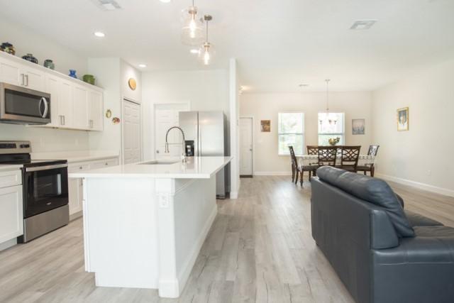 8286 96th Ct, Vero Beach, FL 32967 - kitchen with appliances with stainless steel finishes, a sink, light wood-type flooring, light countertops, and recessed lighting