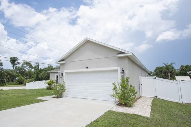 8286 96th Ct, Vero Beach, FL 32967 - view of side of property featuring a gate, a garage, driveway, and stucco siding