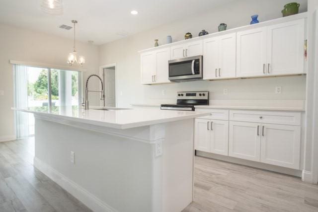 8286 96th Ct, Vero Beach, FL 32967 - kitchen with stainless steel appliances, a sink, light wood-style floors, white cabinets, and recessed lighting