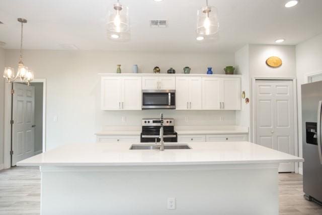 8286 96th Ct, Vero Beach, FL 32967 - kitchen featuring stainless steel appliances, light wood-style flooring, a sink, white cabinets, and light countertops