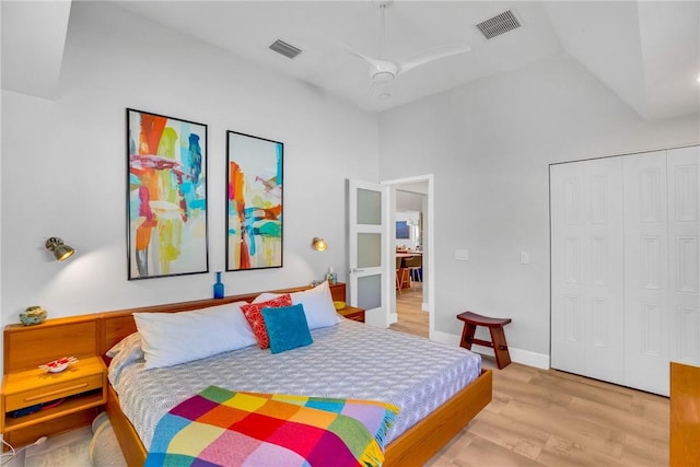 bedroom featuring ceiling fan, a closet, high vaulted ceiling, and light hardwood / wood-style flooring