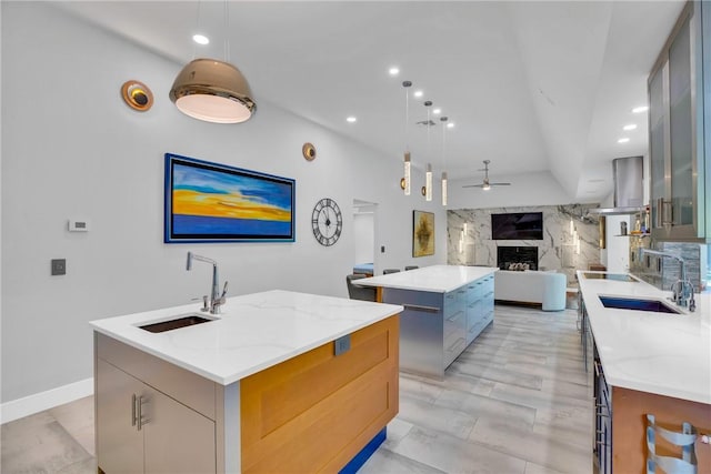 kitchen featuring ceiling fan, decorative light fixtures, a kitchen island with sink, and sink