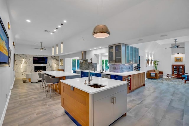 kitchen featuring ceiling fan, hanging light fixtures, a large island with sink, and tasteful backsplash