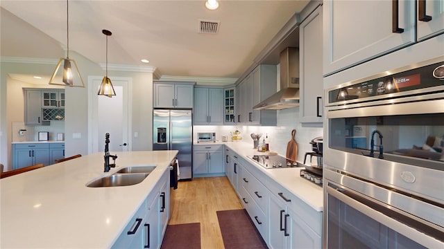 kitchen featuring crown molding, appliances with stainless steel finishes, pendant lighting, sink, and light hardwood / wood-style flooring