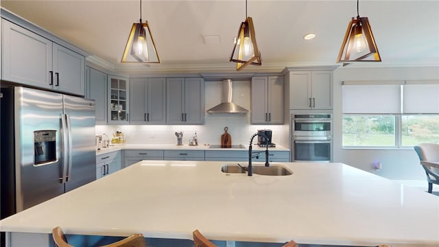 kitchen featuring appliances with stainless steel finishes, gray cabinets, sink, a breakfast bar, and wall chimney exhaust hood