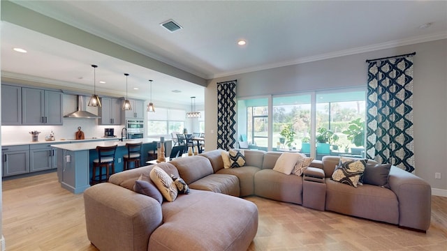 living room featuring light hardwood / wood-style floors, sink, and crown molding